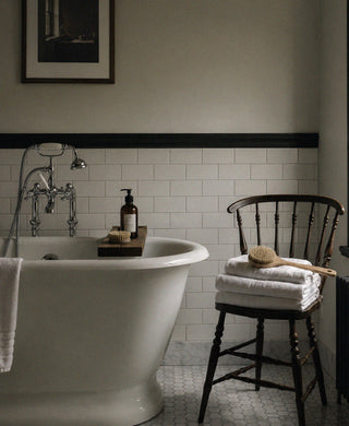 Bathtub beside folded towels and a wooden body brush