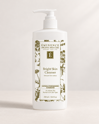 A 250 ml white pump bottle of Eminence Organic Skin Care Bright Skin Cleanser, featuring a white label with green botanical illustrations and text, set against a clean, light beige background.
