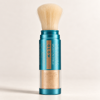 Glow Sunscreen Powder Brush-On Shield stick in a metallic teal tube with a natural beige brush bristle top and a clear lower section showing the beige powder inside, set against a warm off-white background.