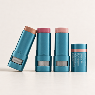 Four metallic teal lip balm tubes arranged on a clean off-white background. Three tubes are open, showing pink and peach-colored balm sticks, and one tube is closed with a peach band.